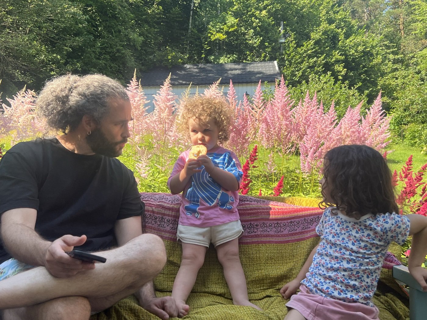 Jonatan and the kids on a garden bench among pink flowers